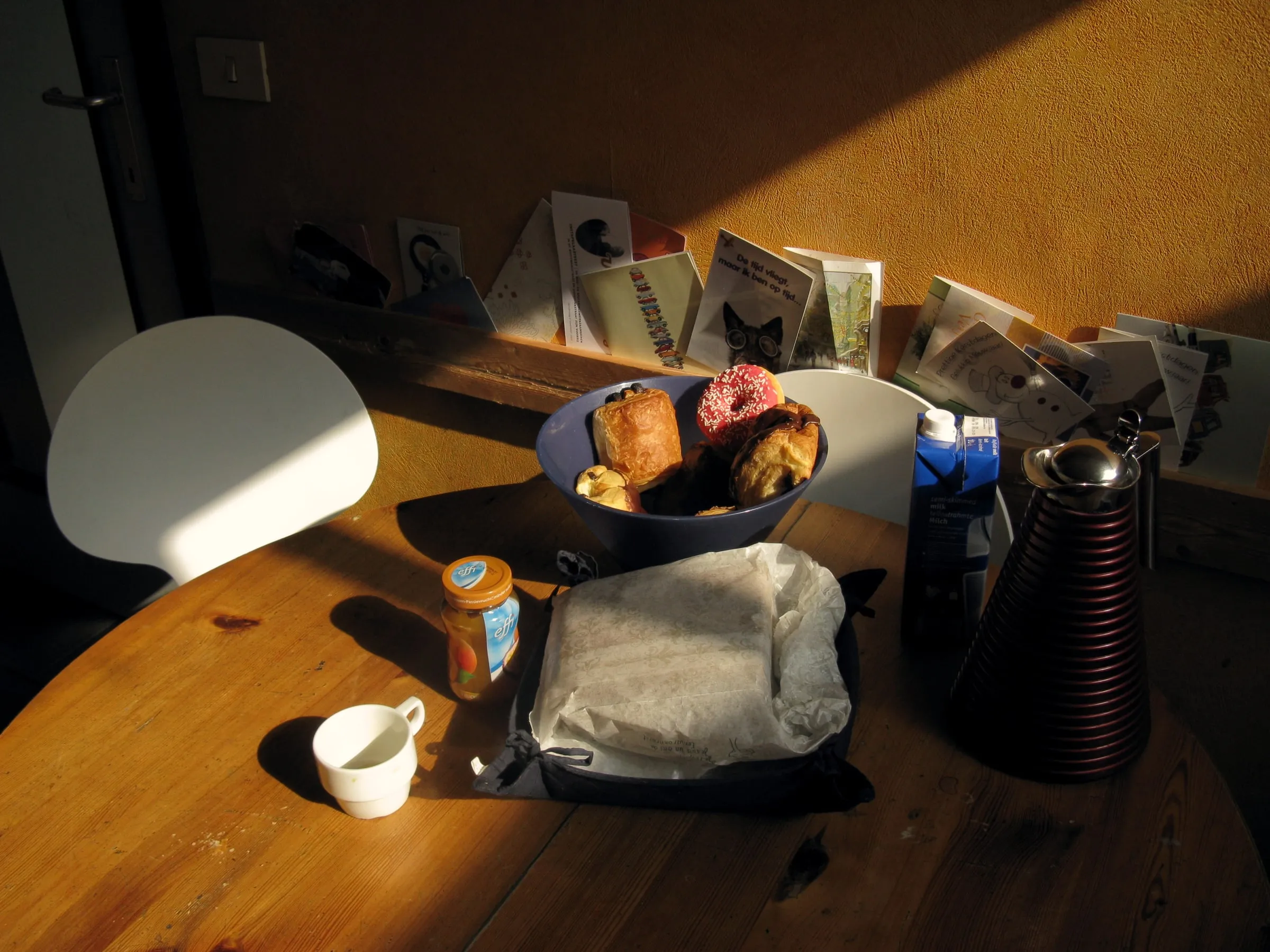 A kitchen worktop in low warm light with a cup, bread and jars, most of the room in shadow