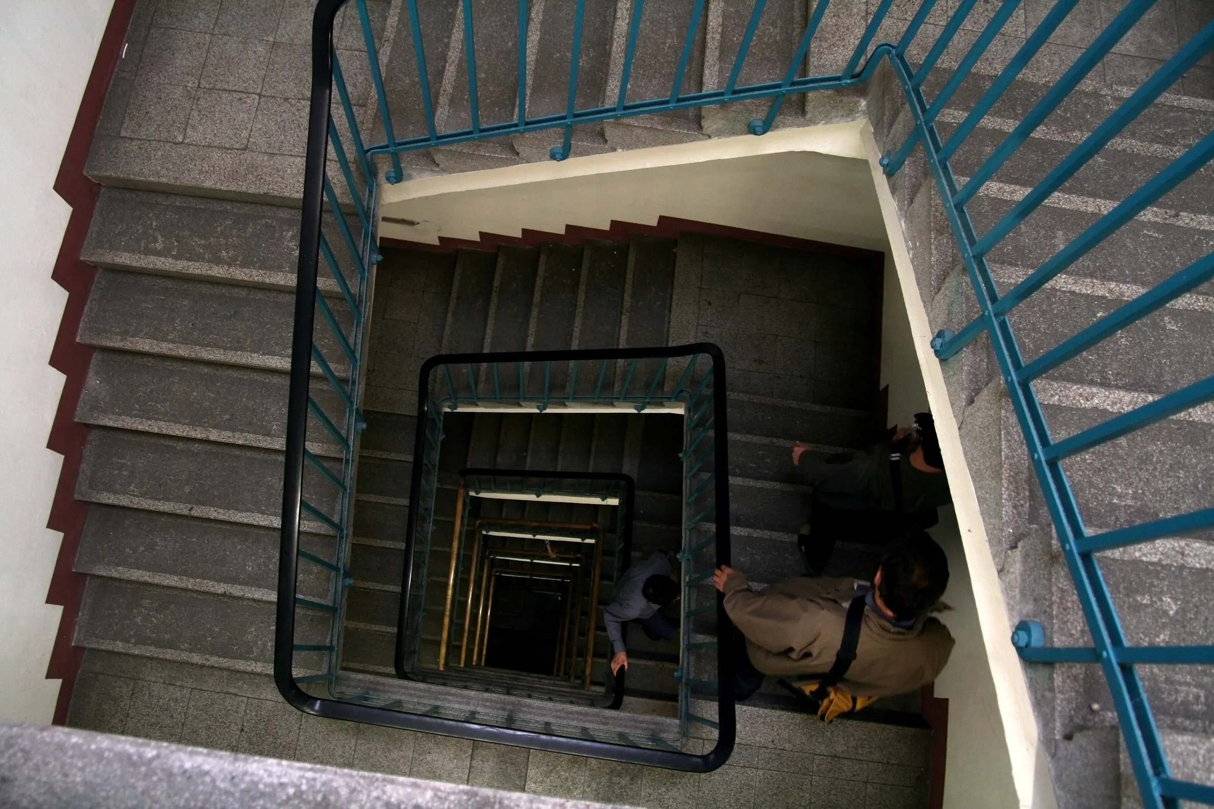 Looking down a concrete stairwell as a person climbs the steps below